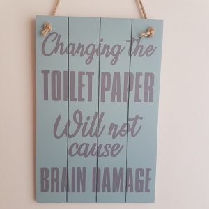 Wooden sign with the text 'Changing the toilet paper will not cause brain damage