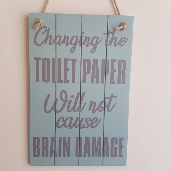 Wooden sign with the text 'Changing the toilet paper will not cause brain damage