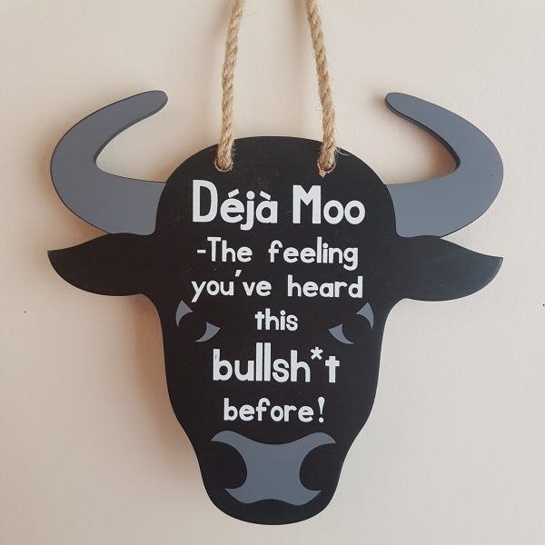 Black bull shaped sign with white text 'Deja Moo - Thee feeling you've heard this bullsh*t before!