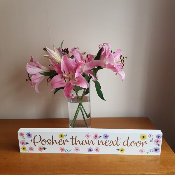 Large white free standing block with the text 'Posher Than Next Door' decorated with colourful flowers