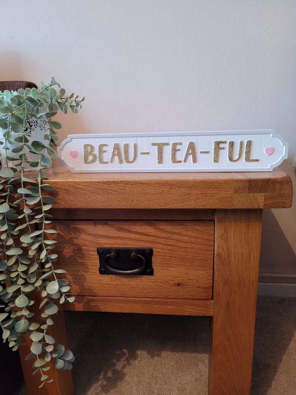A white free standing block with a light grey border with gold glitter text 'Beau-Tea-Ful'. With cute pink hearts either side, a fabulous sign for tea lovers!
