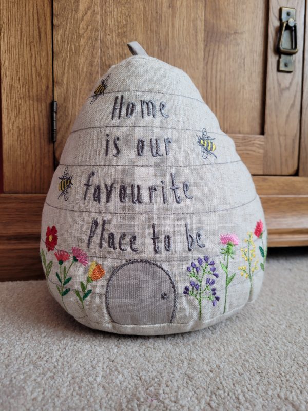 Beautifully embroidered beehive doorstop with the saying; 'Home is our favourite place to be'. Dimensions - 22x27cm